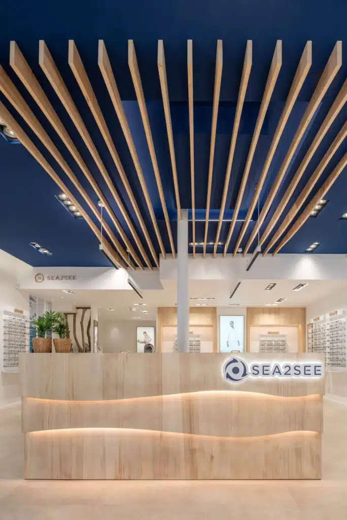 Agencement de boutique sur mesure Sea2See : comptoir d'accueil en bois et claustra design, réalisation menuiserie BOPIK