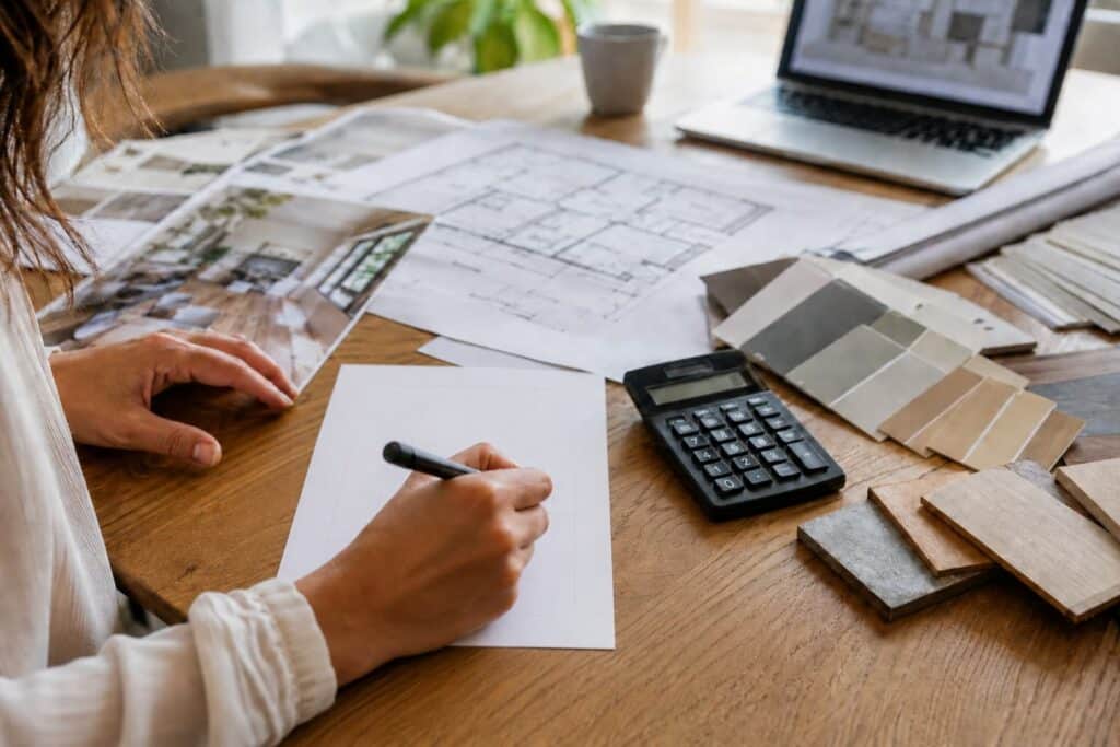 Évaluation financière des travaux lors d’une visite de bien immobilier avec plans, et prise de notes