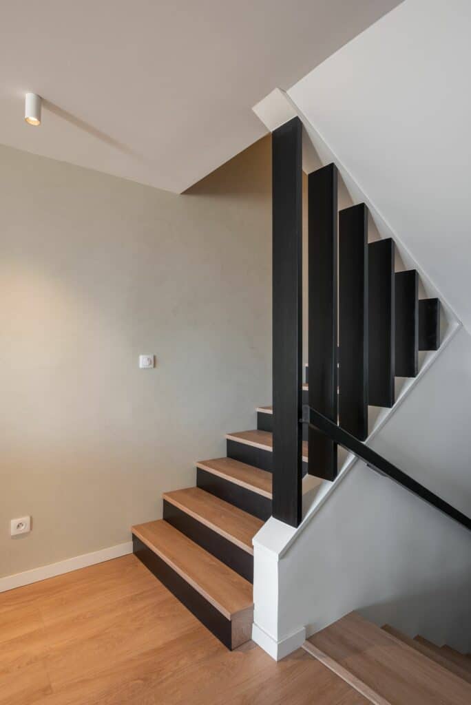 Escalier contemporain en bois et métal noir dans un appartement rénové, projet de décoration intérieure et rénovation dans les Alpes